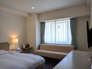 a hotel room with a bed and a couch and a window at Hotel Harbour Yokosuka in Yokosuka