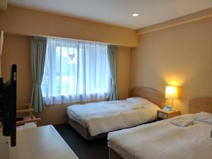 Hotel Harbour Yokosuka في يوكوسوكا: غرفة فندقية بسريرين ونافذة