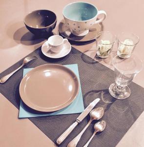 une table avec une plaque, une tasse et de l'argenterie dans l'établissement les Bovrieres, à Cysoing