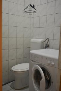 a bathroom with a toilet and a washing machine at Center Apartman - Paks in Paks