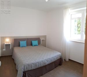 a bedroom with a bed with blue pillows and a window at Case Vacanza Marzano in Monopoli