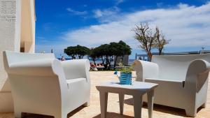 a patio with white chairs and a table with a vase on it at Case Vacanza Marzano in Monopoli