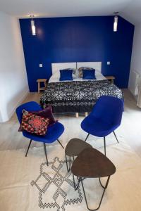 a bedroom with a bed with blue walls and blue chairs at Douce Nuits in Nuits-Saint-Georges