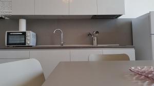 a white kitchen with a microwave and a table at Case Vacanza Marzano in Monopoli