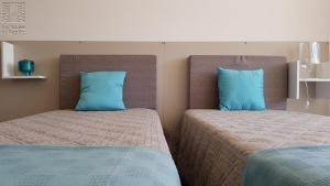 two beds with blue pillows in a bedroom at Case Vacanza Marzano in Monopoli