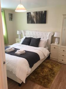 ロンドンにあるCharimore Executive Apartmentのベッドルーム(白黒のシーツを使用した大型の白いベッド付)
