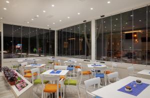 a restaurant with white tables and chairs and windows at Castello Boutique Hotel in Čačak