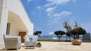 a patio with two white chairs and a view of the ocean at Case Vacanza Marzano in Monopoli