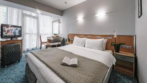 a hotel room with a bed with a book on it at City Park Hotel Sochi in Sochi