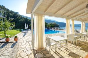 a patio with a table and chairs and a pool at Vliho Bay Suites & Apartments in Yenion
