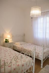 a white bedroom with two beds and a lamp at Villa Kedros in Kalamaki Heraklion