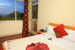 Un dormitorio con una cama con almohadas rojas y una ventana en Haile Resort Ziway Batu, en Ziway