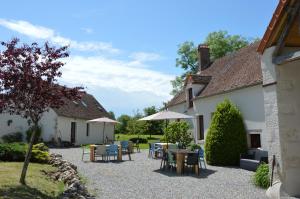 a courtyard of a house with tables and umbrellas at Chambres d'hôtes Maison Les Galettes in Rezay
