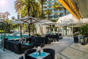 un patio con sedie e ombrelloni accanto alla piscina di Hotel Cannes Montfleury a Cannes