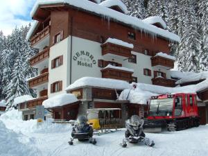 two people on skis in the snow in front of a hotel at Hotel Gembro in Chiesa in Valmalenco