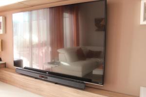 TV con silla blanca en la habitación en Oasis Beach 5, en Playas de Orihuela