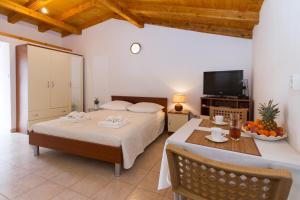 a bedroom with two beds and a table and a tv at Beach apartment M & B in Poljana