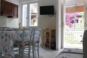 comedor con mesa, sillas y TV en Casa Azzurra 3 camere e 2 bagni en Fetovaia