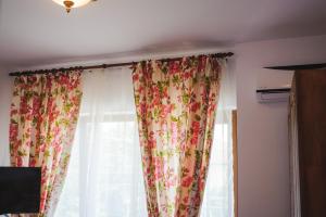 a window with floral curtains in a room at Pensiunea Geostar in Curtea de Argeş +119 photos