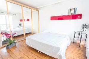 ein weißes Schlafzimmer mit einem Bett und einem großen Fenster in der Unterkunft Luxury Apartment in Paris Center - Louvre Museum in Paris