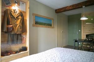 Angoville-au-PlainにあるDomaine Airborneのベッド1台付きの部屋、壁にジャケットが付いています。
