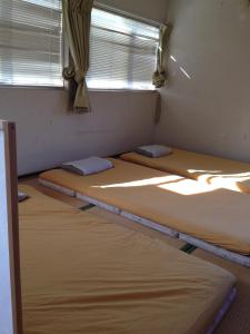 3 camas en una habitación con ventana en Narita Airport Hostel, en Shibayama