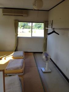 Habitación con 2 camas, ventilador y ventana. en Narita Airport Hostel, en Shibayama