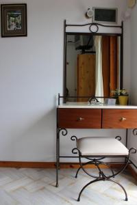 a bathroom with a vanity with a mirror and a chair at Olympion Apartments in Stafylos