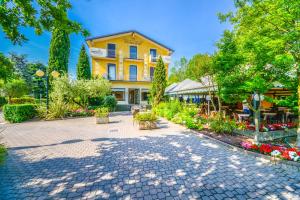 a yellow building with trees and flowers in a courtyard at Hotel Riel in Sirmione