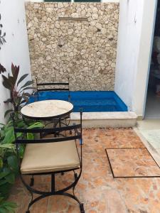 una mesa y 2 sillas frente a una pared de piedra en Aparthotel Siete 32, en Mérida