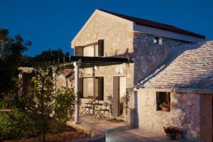 a stone house with a patio and a table at Holiday House KALIMERO in Primošten
