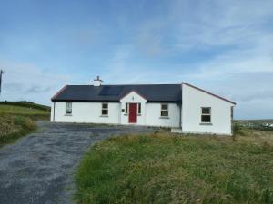 a white house with a red door on a field at Mary's Meadow in Doolin