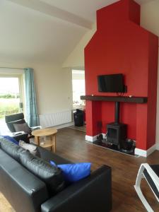 ein Wohnzimmer mit einem schwarzen Sofa und einer roten Wand in der Unterkunft Mary's Meadow in Doolin