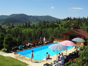 un grupo de personas sentadas alrededor de una piscina en Alpenhof Pansion, en Slavske