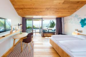 Schlafzimmer mit einem Bett, einem Schreibtisch und einem Tisch in der Unterkunft Hotel Seehof in Immenstaad am Bodensee