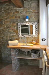 Un baño con lavabo y pared de piedra. en La Corte del Gusto LuxuryApartments, en Arcevia