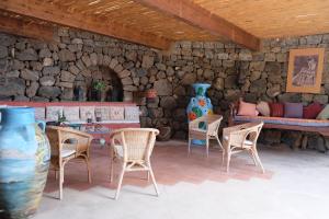 a room with chairs and a stone wall at Dammuso Il Sogno in Scauri