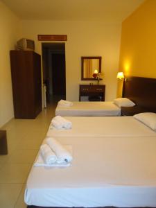 a hotel room with four beds with towels on them at Hotel Zachos in Troulos