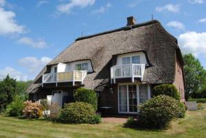 ein strohgedecktes Haus mit einer Veranda und einem Balkon in der Unterkunft Appartement Beisel unter Reet in Garding