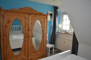 ein Schlafzimmer mit einer Holzkommode und einem Spiegel in der Unterkunft Appartement Beisel unter Reet in Garding