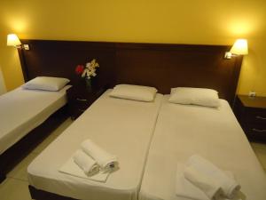 two beds in a hotel room with towels and a vase of flowers at Hotel Zachos in Troulos