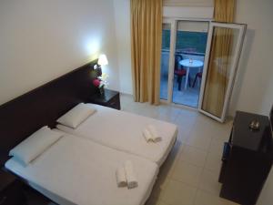 a bedroom with a white bed with slippers on it at Hotel Zachos in Troulos