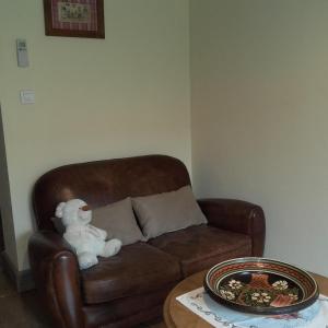 a stuffed teddy bear sitting on a brown couch at Gite chez Marianne et Marcel in Ebersheim