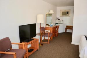 um quarto de hotel com uma televisão de ecrã plano e cadeiras em Sage Motel em Newcastle