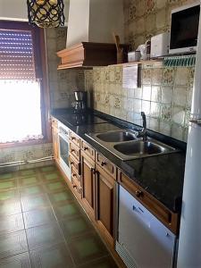 cocina con fregadero y fogones en Apartamentos Turísticos Luar II, en El Rasillo