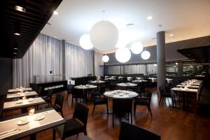 a dining room with tables and chairs and lights at Hotel Carris Marineda in A Coruña