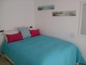 um quarto com uma cama azul e 2 almofadas em Beachfront House em Málaga