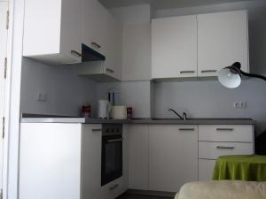 a kitchen with white cabinets and a sink at Apartment on the beach in Málaga