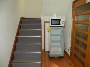 a microwave oven sitting on top of a refrigerator next to stairs at Business Hotel Minshuku Minato in Tokushima