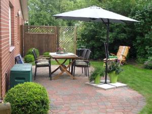 eine Terrasse mit einem Tisch, Stühlen und einem Sonnenschirm in der Unterkunft Ferienwohnung "Abendröte" in Lüdersburg